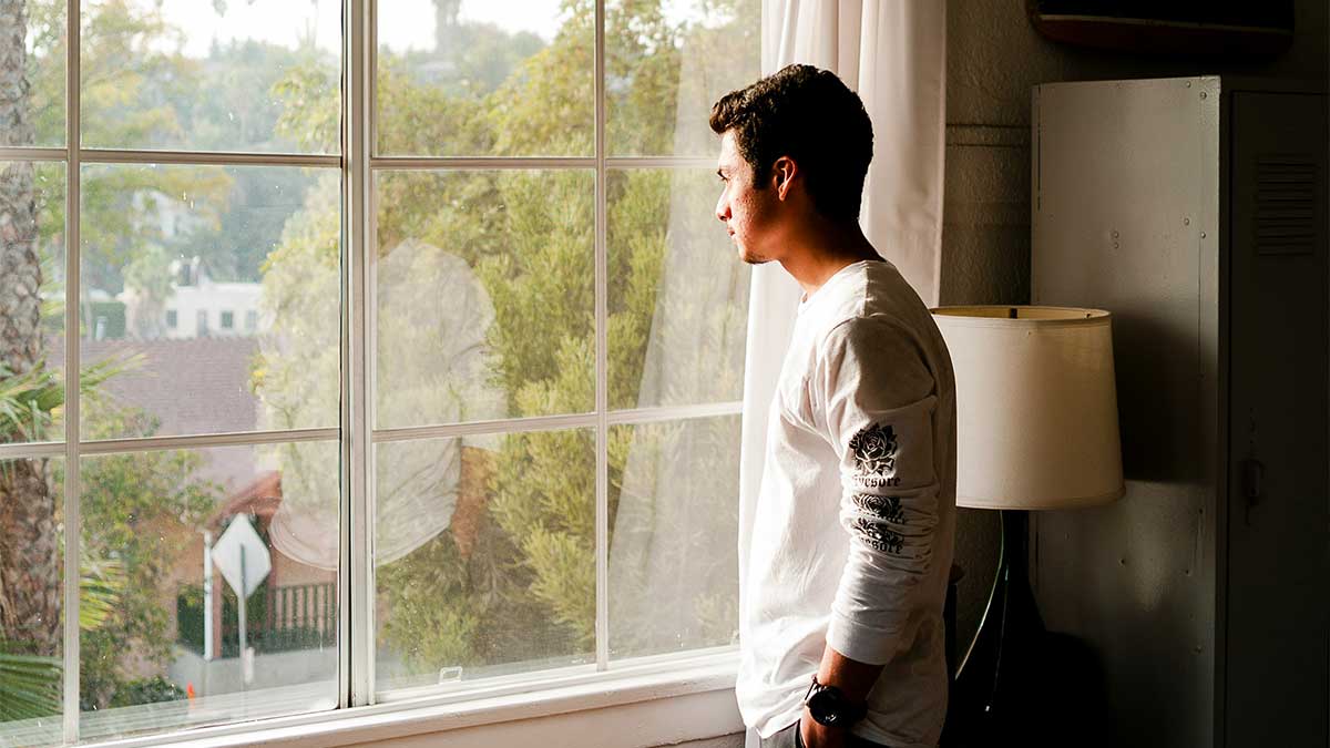 Yksinäinen mies katsoo ikkunasta ulos